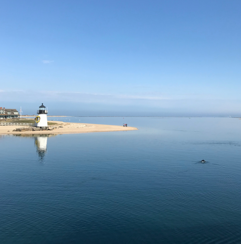 Lighthouse on a beach with wide view of a clear sea and sky